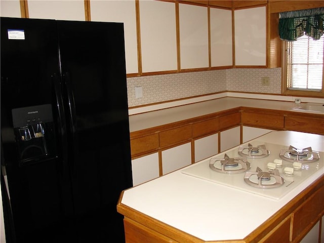 kitchen featuring decorative backsplash, white cabinetry, white gas cooktop, and black refrigerator with ice dispenser