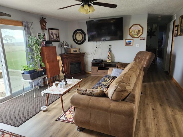 living room featuring wood-type flooring, a textured ceiling, and ceiling fan