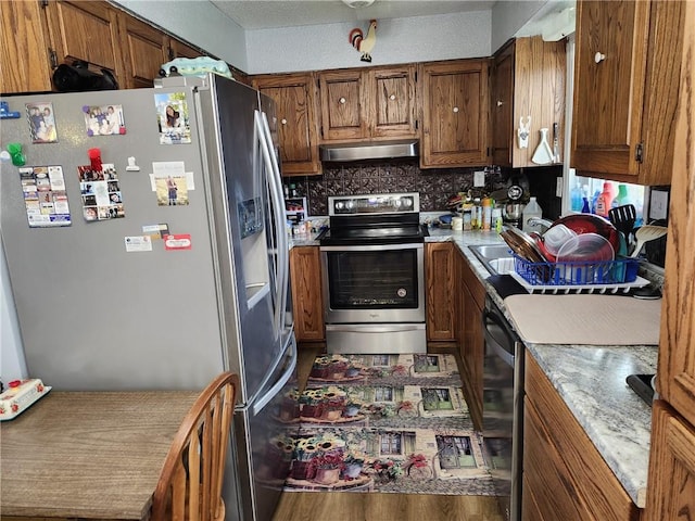 kitchen with decorative backsplash, appliances with stainless steel finishes, and wood-type flooring