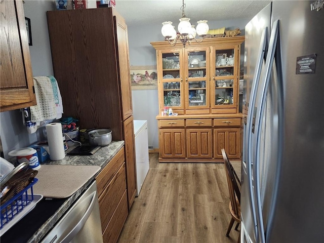 kitchen featuring pendant lighting, light hardwood / wood-style floors, stainless steel refrigerator, and an inviting chandelier