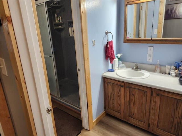 bathroom with wood-type flooring, vanity, and an enclosed shower