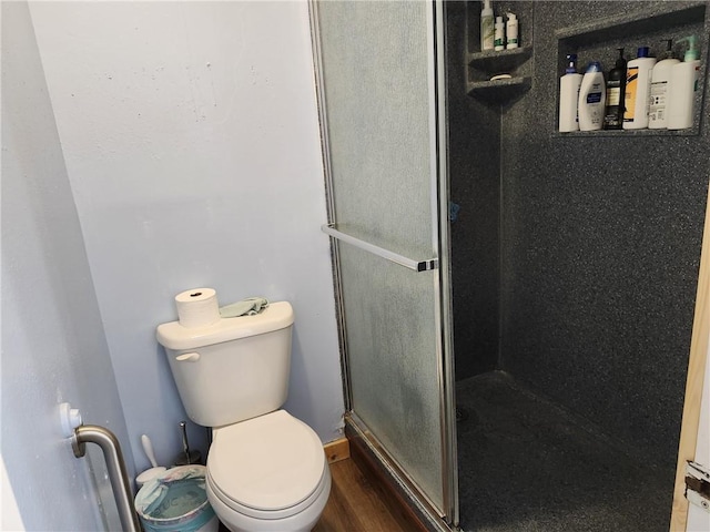 bathroom with hardwood / wood-style floors, a shower with shower door, and toilet