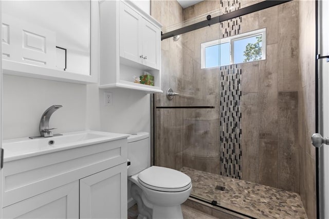 bathroom featuring vanity, a shower with shower door, and toilet