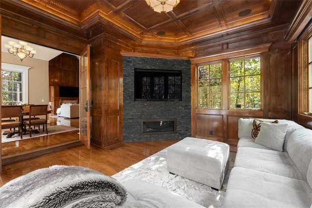 living room with hardwood / wood-style flooring, a stone fireplace, and ornamental molding