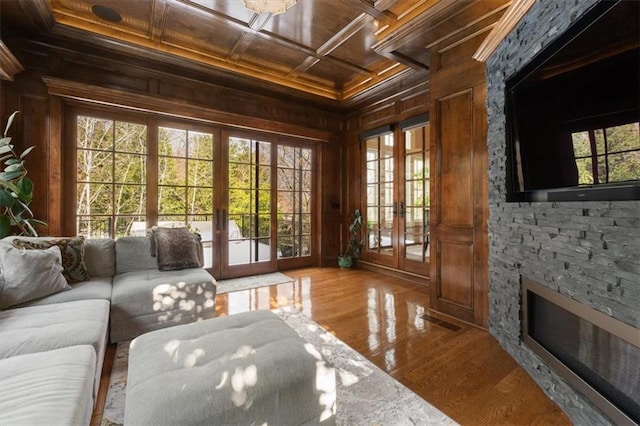 living room with wood walls, french doors, wood ceiling, and light wood-type flooring