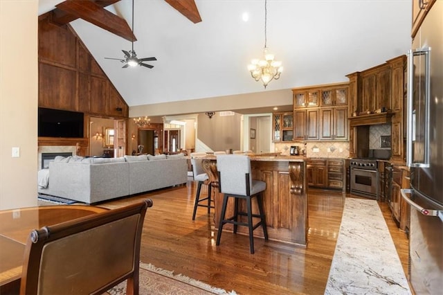 kitchen featuring a kitchen breakfast bar, premium appliances, pendant lighting, high vaulted ceiling, and hardwood / wood-style floors