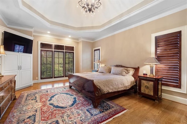 bedroom with a tray ceiling, crown molding, a notable chandelier, and light wood-type flooring