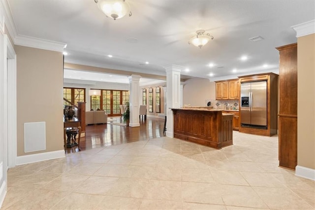 kitchen featuring kitchen peninsula, stainless steel fridge, crown molding, and ornate columns