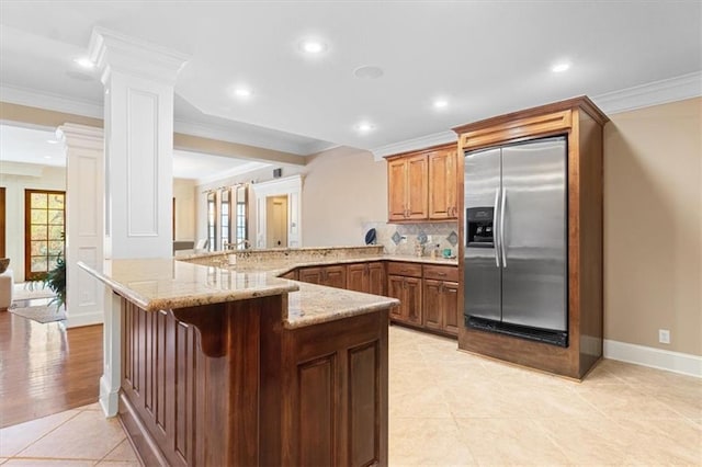 kitchen with kitchen peninsula, backsplash, crown molding, a breakfast bar area, and built in fridge