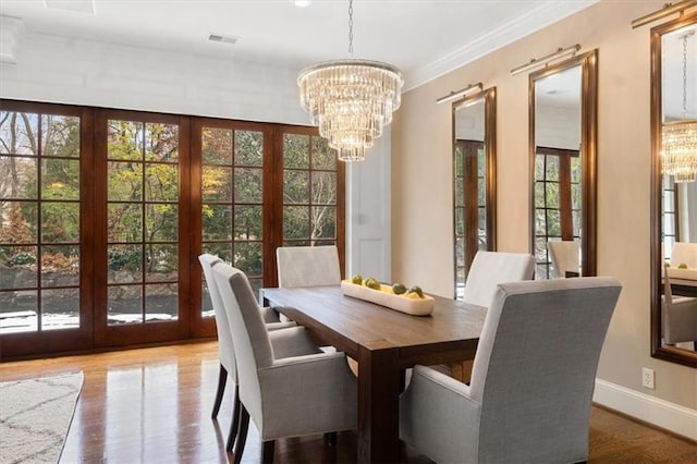 dining space featuring french doors, an inviting chandelier, light hardwood / wood-style flooring, and ornamental molding