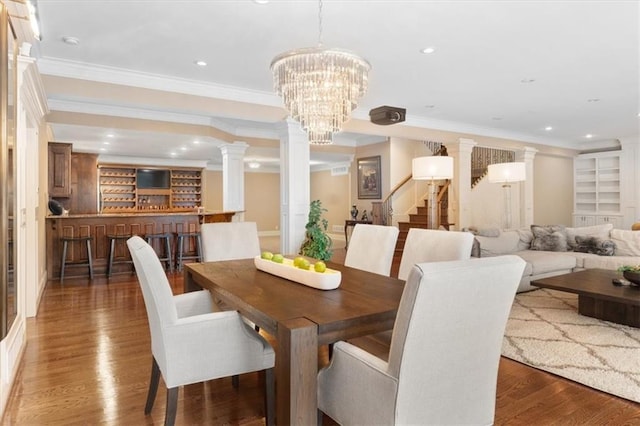 dining space featuring dark hardwood / wood-style flooring, decorative columns, ornamental molding, built in features, and a chandelier