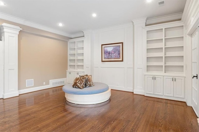 unfurnished room with wood-type flooring, built in shelves, and ornamental molding