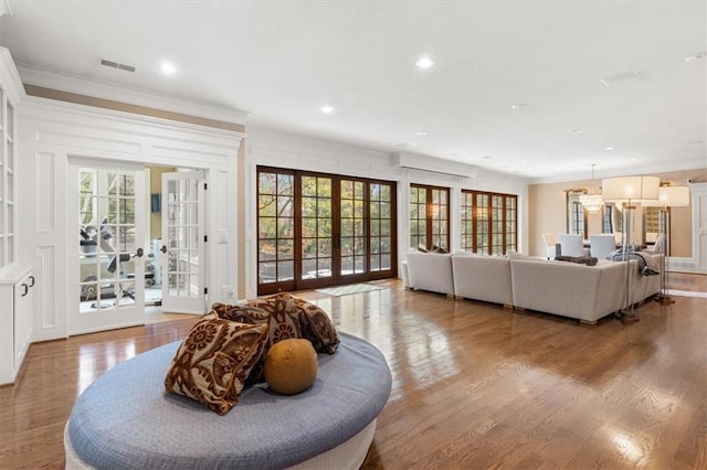 living room with hardwood / wood-style flooring, a healthy amount of sunlight, ornamental molding, and french doors