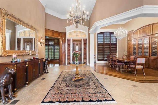 tiled entryway featuring crown molding, high vaulted ceiling, and a chandelier