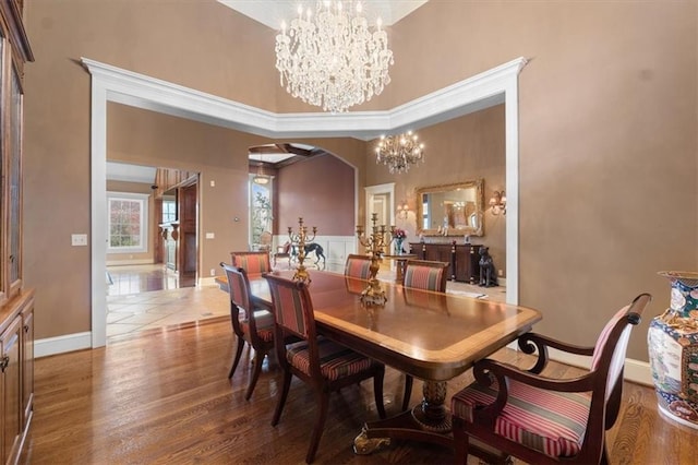 dining room featuring hardwood / wood-style floors, a towering ceiling, and an inviting chandelier