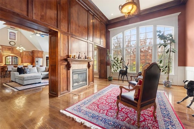 living area featuring ceiling fan with notable chandelier, crown molding, high vaulted ceiling, and light hardwood / wood-style flooring