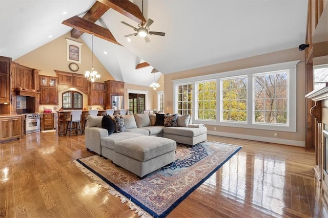 living room featuring hardwood / wood-style flooring, ceiling fan with notable chandelier, beam ceiling, and high vaulted ceiling