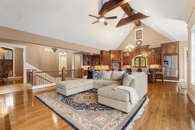 living room featuring beam ceiling, high vaulted ceiling, ceiling fan with notable chandelier, and hardwood / wood-style flooring