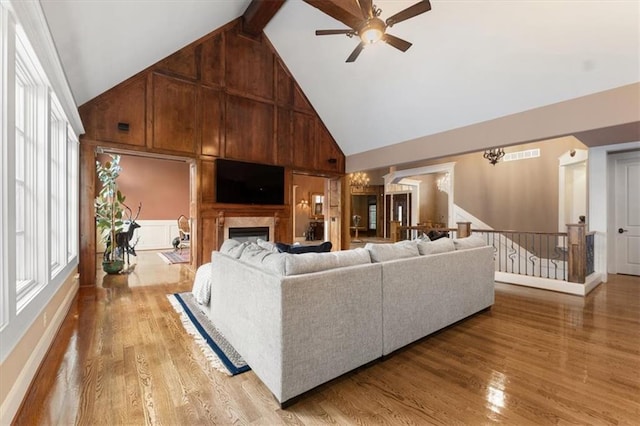 living room featuring ceiling fan with notable chandelier, light hardwood / wood-style flooring, high vaulted ceiling, and a wealth of natural light