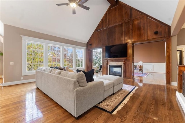 living room featuring ceiling fan, light wood-type flooring, and high vaulted ceiling