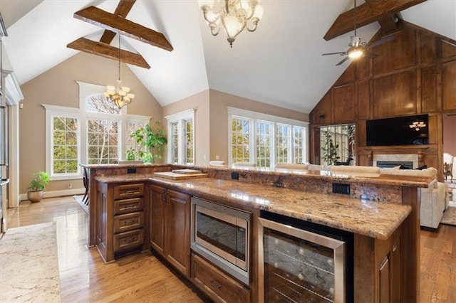 kitchen with plenty of natural light, stainless steel microwave, beverage cooler, and light hardwood / wood-style flooring