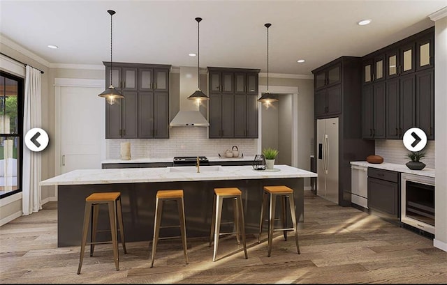 kitchen featuring dark brown cabinetry, a large island, beverage cooler, wall chimney range hood, and stainless steel fridge