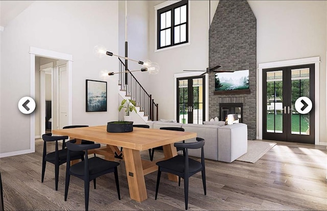 dining space with hardwood / wood-style flooring, ceiling fan with notable chandelier, high vaulted ceiling, and french doors