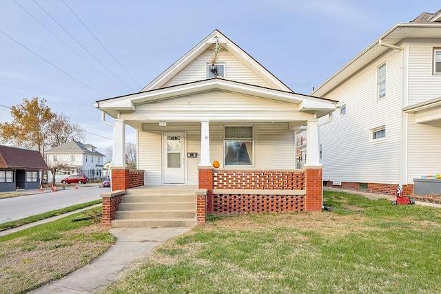 bungalow with covered porch and a front lawn