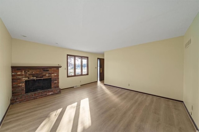 unfurnished living room with a brick fireplace and light wood-type flooring