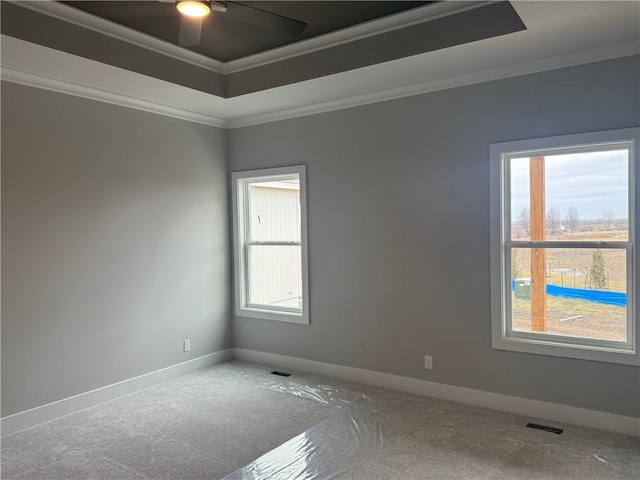 unfurnished room featuring baseboards, a tray ceiling, visible vents, and crown molding