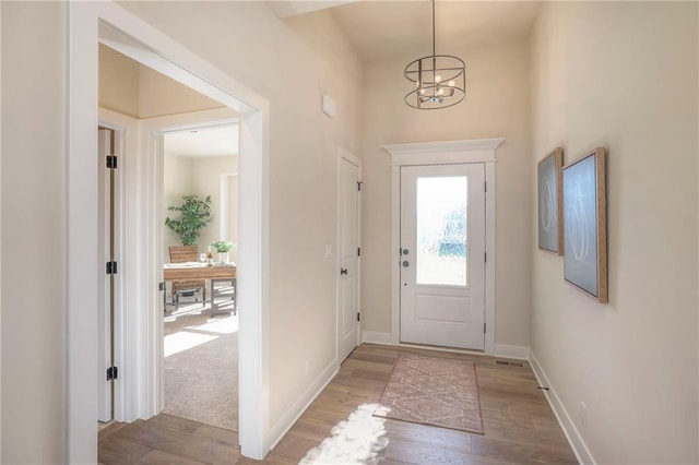 entrance foyer featuring a notable chandelier, wood finished floors, visible vents, and baseboards