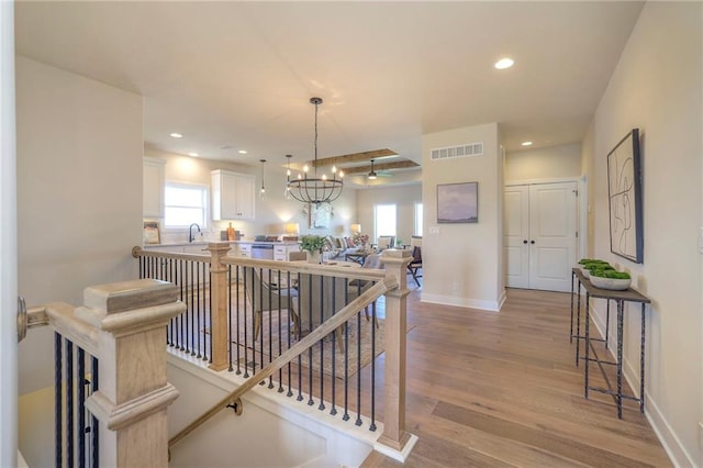 hallway with visible vents, baseboards, an upstairs landing, light wood-type flooring, and recessed lighting