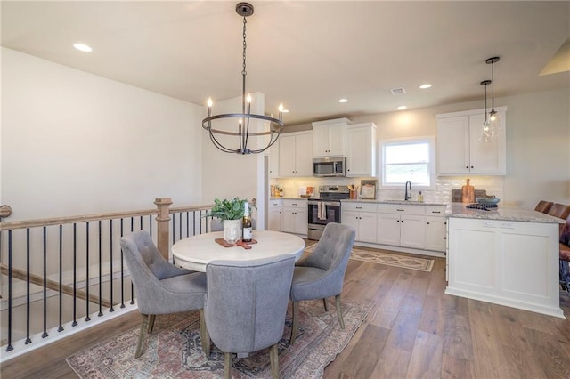 dining room with dark wood-type flooring, recessed lighting, and a notable chandelier