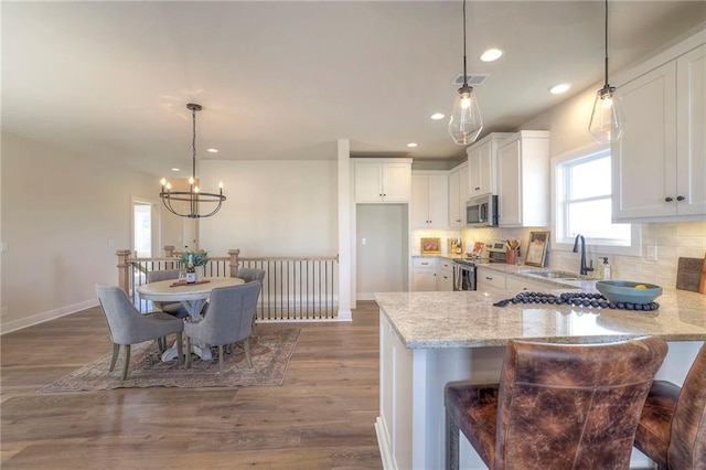 kitchen with visible vents, decorative backsplash, light stone counters, stainless steel appliances, and a sink