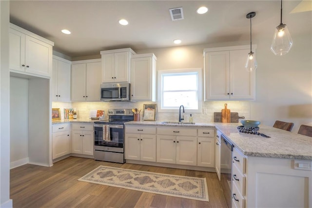 kitchen with visible vents, appliances with stainless steel finishes, white cabinets, a sink, and a peninsula