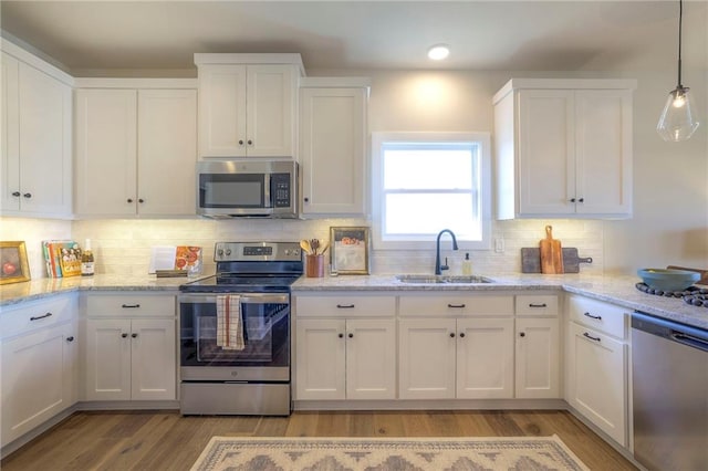 kitchen with appliances with stainless steel finishes, a sink, and white cabinetry