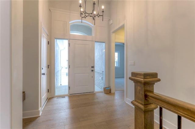 foyer featuring a healthy amount of sunlight, a notable chandelier, and light wood-type flooring