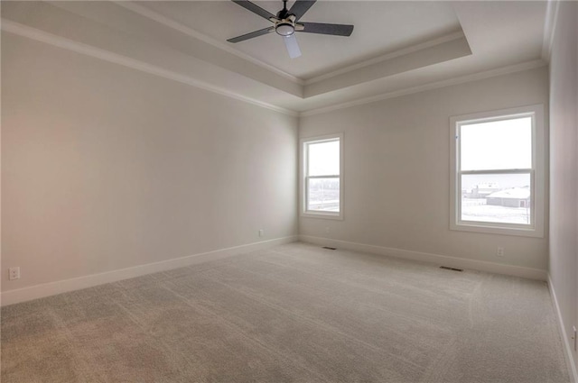 empty room with light carpet, a tray ceiling, ornamental molding, and ceiling fan