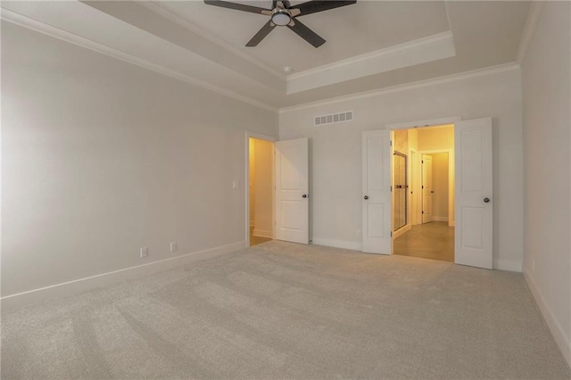 unfurnished bedroom featuring a raised ceiling, crown molding, light colored carpet, and ceiling fan