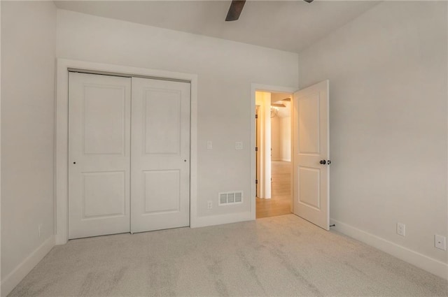 unfurnished bedroom with light carpet, a closet, and ceiling fan