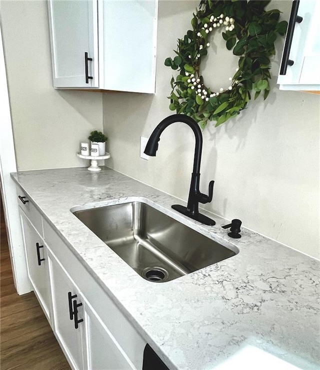 interior space with sink, white cabinetry, light stone counters, and dark hardwood / wood-style floors