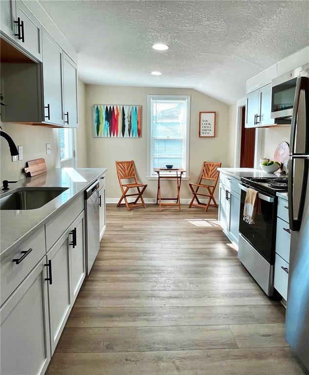 kitchen with sink, stainless steel appliances, white cabinetry, and a textured ceiling