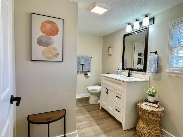 bathroom featuring hardwood / wood-style floors, toilet, vanity, and a textured ceiling