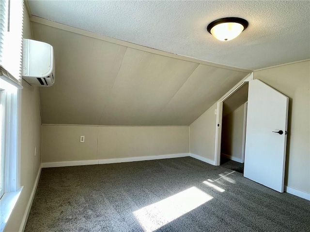 bonus room with dark carpet, lofted ceiling, a textured ceiling, and a wall mounted air conditioner