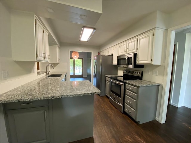 kitchen featuring white cabinetry, sink, light stone countertops, kitchen peninsula, and appliances with stainless steel finishes