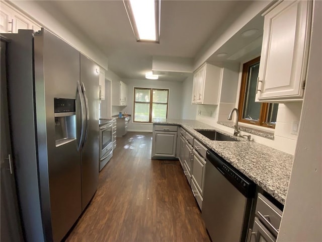 kitchen with light stone countertops, sink, stainless steel appliances, dark hardwood / wood-style floors, and white cabinets