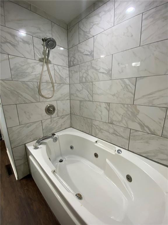 bathroom with hardwood / wood-style floors and tiled shower / bath combo