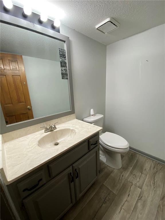 bathroom featuring toilet, vanity, a textured ceiling, and hardwood / wood-style flooring