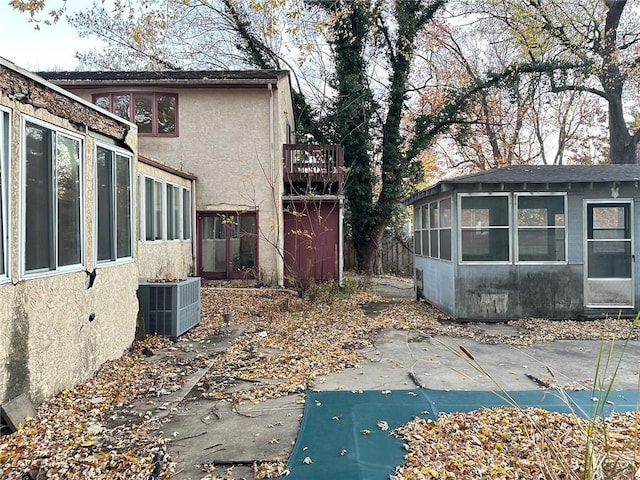 view of side of home featuring a patio, a balcony, central AC unit, and a sunroom