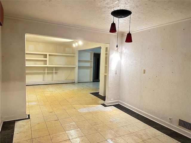 empty room featuring built in shelves, a textured ceiling, and crown molding